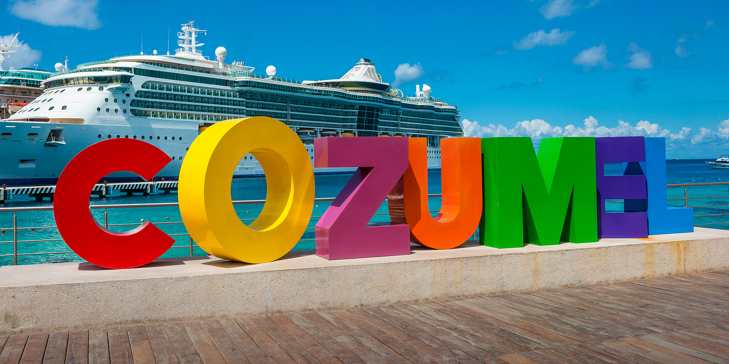 A cruise ship anchored near the Cozumel sign at the port. | Source: Shutterstock