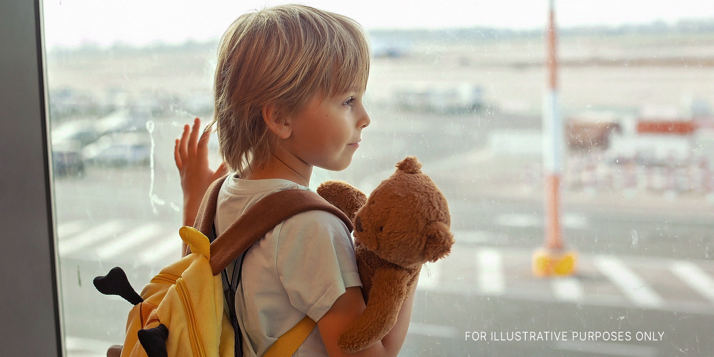 A little boy holding a stuffed animal while gazing out an airport window | Source: Getty Images