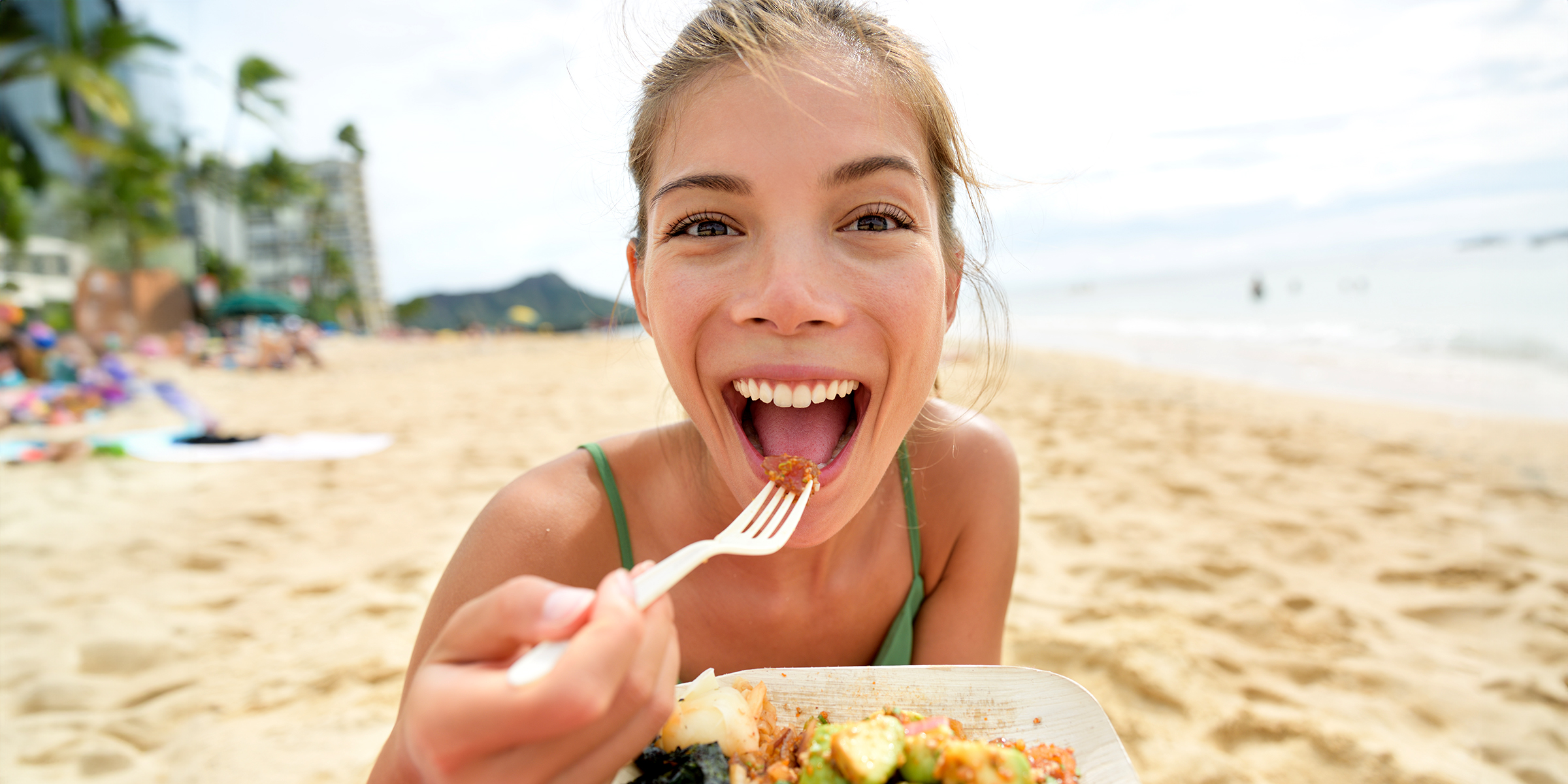 A woman enjoys food by the beach | Source: Shutterstock